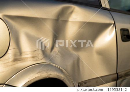 Large dent on silver car body after collision 139538142