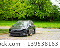 Front view of damaged black car parked on road 139538163