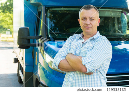 Confident truck driver with arms crossed near van Confident truck driver with arms crossed near van 139538185