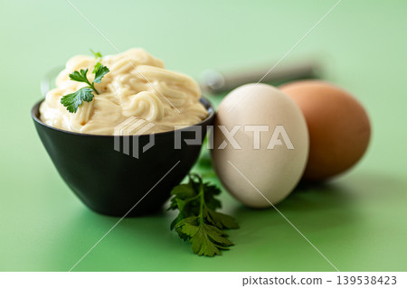 creamy mayonnaise sauce in bowl on green background creamy mayonnaise sauce in bowl on green background 139538423