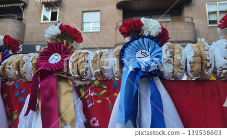 Traditional spanish festival decorated pastry ring with blue and red ribbons and carnations in colmenar viejo for festival banner and background design. Feria La Vaquilla, Colmenar Viejo, Spain Traditional spanish festival decorated pastry ring with blue and red ribbons and carnations in colmenar viejo for festival banner and background design. Feria La Vaquilla, Colmenar Viejo, Spain 139538603
