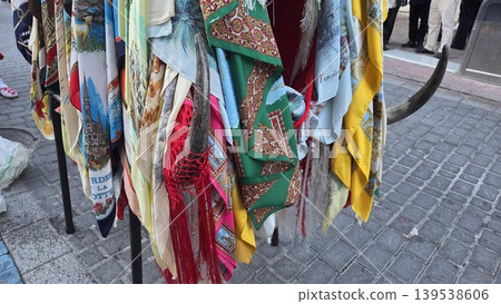 Colorful hanging scarves and traditional shawls displayed on stand with fringes and patterned fabrics for la vaquilla colmenar viejo festival market background Colorful hanging scarves and traditional shawls displayed on stand with fringes and patterned fabrics for la vaquilla colmenar viejo festival market background 139538606