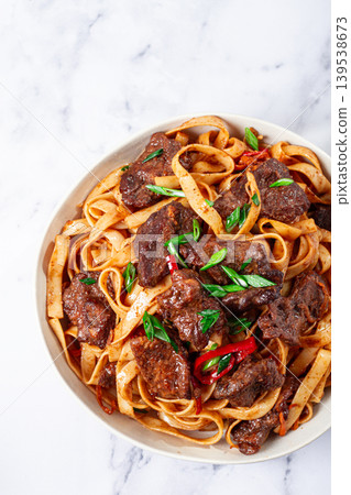 Udon noodles with Mongolian beef, green onions and vegetables, in a white plate, on a light background, homemade, no people, Udon noodles with Mongolian beef, green onions and vegetables, in a white plate, on a light background, homemade, no people, 139538673