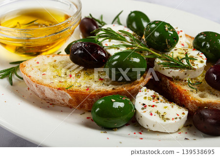 a plate with a snack, ciabatta bread with cheese and olives, olive oil, spices and herbs, top view, no people, 139538695
