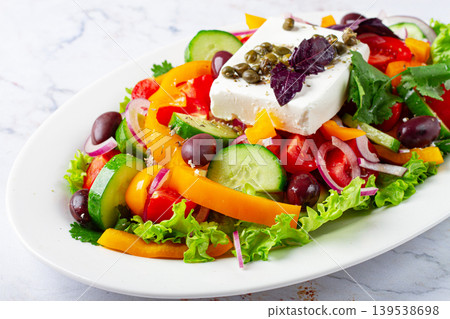 Greek salad, with vegetables and feta cheese, served on a white plate, no people. Greek salad, with vegetables and feta cheese, served on a white plate, no people. 139538698