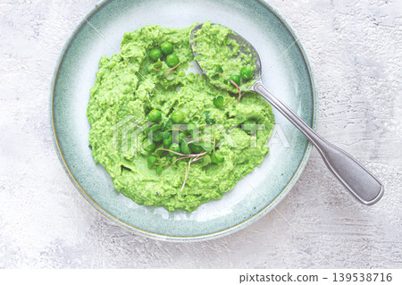 Delicious green pea puree served in a stylish bowl garnished with fresh peas and microgreens for a healthy meal Delicious green pea puree served in a stylish bowl garnished with fresh peas and microgreens for a healthy meal 139538716