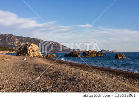 Pebble beach with large coastal rocks and blue sea Pebble beach with large coastal rocks and blue sea 139538861