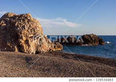 Large rock formation on a pebble beach at mediterranean sea Large rock formation on a pebble beach at mediterranean sea 139538863