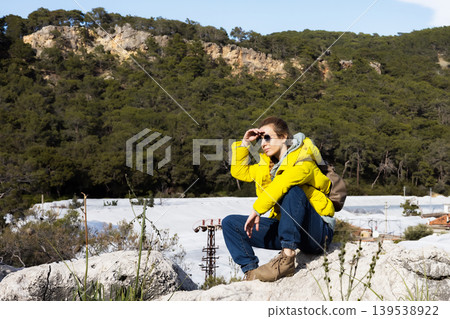 Young woman in yellow jacket resting on a mountain ridge Young woman in yellow jacket resting on a mountain ridge 139538922
