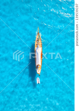Vertical aerial drone view of yacht floating on azure sea water. Vertical aerial drone view of yacht floating on azure sea water. 139539197
