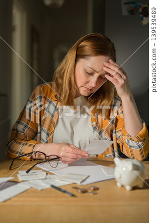 Household budgeting and financial stress concept with woman checking bills at home Household budgeting and financial stress concept with woman checking bills at home 139539489