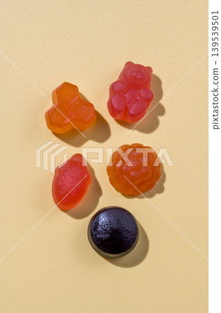 Food supplements. Vitamins jelly gummies fruit and bear shaped on yellow background Food supplements. Vitamins jelly gummies fruit and bear shaped on yellow background 139539501