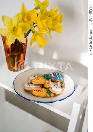 Easter spring background. Easter cookies with colourful icing: bunnies, carrots and eggs in a plate with bouquet of fresh. Bright and airy photo Easter spring background. Easter cookies with colourful icing: bunnies, carrots and eggs in a plate with bouquet of fresh. Bright and airy photo 139539553