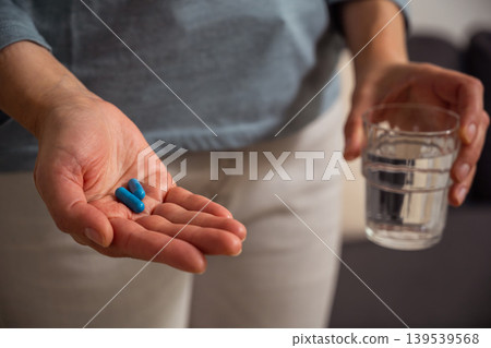 Woman holding blue pills in hand. Health care, dietary supplements, treatment of depression and diseases Woman holding blue pills in hand. Health care, dietary supplements, treatment of depression and diseases 139539568
