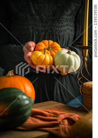 Orange, green and white squashes, female hands holding pumpkin, rustic wooden moody background, autumn concept 139539586