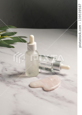 Rose quartz gua sha and oil bottles, abstract beauty photo Rose quartz gua sha and oil bottles, abstract beauty photo 139539587