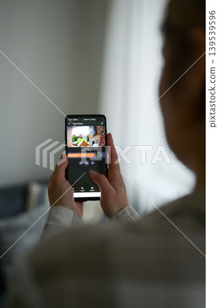 Closeup of a woman using a smartphone app to watch a delivery man dropping off a package 139539596