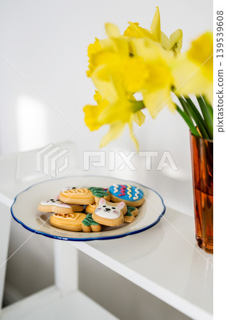 Easter spring background. Easter cookies with colourful icing: bunnies, carrots and eggs in a plate with bouquet of fresh. Bright and airy photo Easter spring background. Easter cookies with colourful icing: bunnies, carrots and eggs in a plate with bouquet of fresh. Bright and airy photo 139539608
