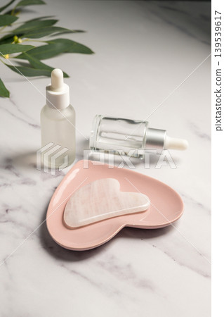 Rose quartz gua sha tool and oil bottles, face massage tool, beauty abstract photo Rose quartz gua sha tool and oil bottles, face massage tool, beauty abstract photo 139539617