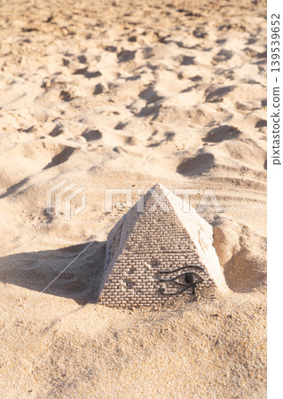 A small stone replica of a pyramid is hidden in the sandy beach, creating a scenic and symbolic landscape 139539652