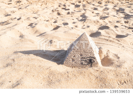 A small stone replica of a pyramid is hidden in the sandy beach, creating a scenic and symbolic landscape 139539653