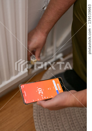 Smartphone connecting to heating radiator. Remote home control system on a smartphone. 139539663
