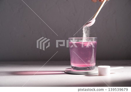 Pouring food supplement powder in glass of water. Collagen, protein powder, vitamins. 139539679