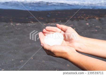 woman meditating on beach shore and holding crystal heart woman meditating on beach shore and holding crystal heart 139539711