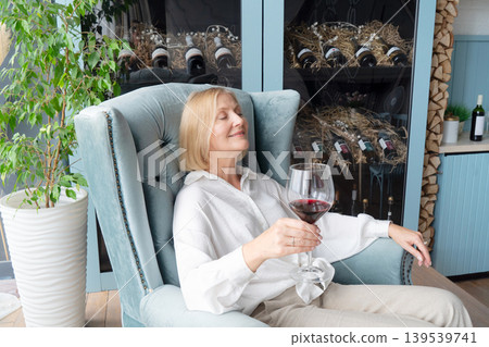 An Elegant Woman Joyfully Toasting with a Glass of Rich Red Wine in a Beautifully Stylish Kitchen Space An Elegant Woman Joyfully Toasting with a Glass of Rich Red Wine in a Beautifully Stylish Kitchen Space 139539741