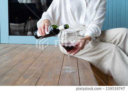 An Elegant Woman Joyfully Toasting with a Glass of Rich Red Wine in a Beautifully Stylish Kitchen Space An Elegant Woman Joyfully Toasting with a Glass of Rich Red Wine in a Beautifully Stylish Kitchen Space 139539747