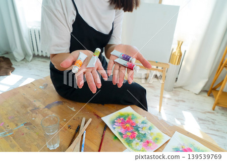 A Creative Artist is diligently at work in a bright and vibrant studio surrounded by stunning floral paintings A Creative Artist is diligently at work in a bright and vibrant studio surrounded by stunning floral paintings 139539769