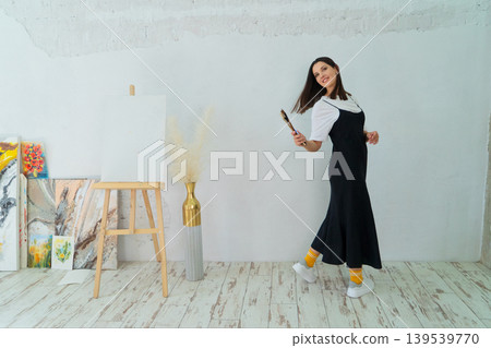 A Creative Artist is diligently at work in a bright and vibrant studio surrounded by stunning floral paintings A Creative Artist is diligently at work in a bright and vibrant studio surrounded by stunning floral paintings 139539770