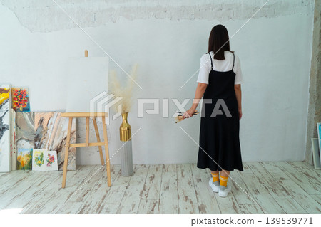 A Creative Artist is diligently at work in a bright and vibrant studio surrounded by stunning floral paintings A Creative Artist is diligently at work in a bright and vibrant studio surrounded by stunning floral paintings 139539771