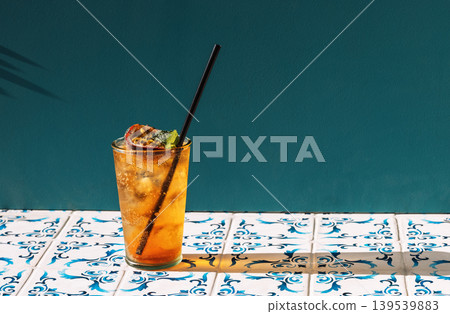 A cool cup of fruit soda with ice cubes on the table with patterned tiles 139539883