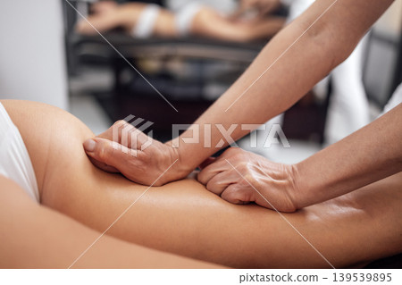 Masseuse makes anti cellulite massage of buttocks, thighs and legs to her client Masseuse makes anti cellulite massage of buttocks, thighs and legs to her client 139539895