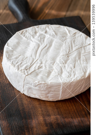 Whole Camembert Cheese Wheel Resting On Dark Rustic Wooden Serving Board Elegantly Whole Camembert Cheese Wheel Resting On Dark Rustic Wooden Serving Board Elegantly 139539996