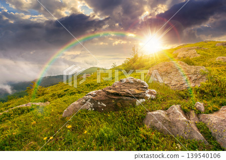 sunset over green landscape of mountain in summer. view of rock among grass on the hillside. travel background under a cloudy sky. mountain scenery with rolling hills. weather with rainbow sunset over green landscape of mountain in summer. view of rock among grass on the hillside. travel background under a cloudy sky. mountain scenery with rolling hills. weather with rainbow 139540106