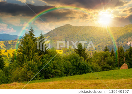 sunset over mountain hay field. alpine countryside summer landscape with green valley behind the woods on the grassy slope. cloudy sky. spectacular highland background under the rainbow sunset over mountain hay field. alpine countryside summer landscape with green valley behind the woods on the grassy slope. cloudy sky. spectacular highland background under the rainbow 139540107
