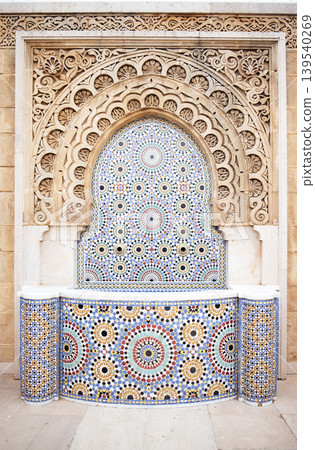 Intricate architectural fountain featuring colorful mosaic tiles and ornate stone carvings, showcasing traditional craftsmanship and cultural artistry in a serene environment Intricate architectural fountain featuring colorful mosaic tiles and ornate stone carvings, showcasing traditional craftsmanship and cultural artistry in a serene environment 139540269