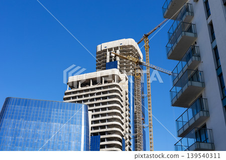 Vibrant urban construction scene featuring towering cranes and reflective glass surfaces Vibrant urban construction scene featuring towering cranes and reflective glass surfaces 139540311