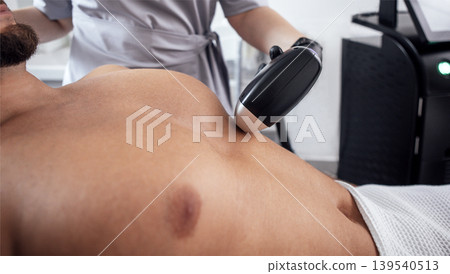 Male patient receiving non-invasive body treatment in a modern clinic, with a professional technician using advanced equipment for skin rejuvenation and wellness Male patient receiving non-invasive body treatment in a modern clinic, with a professional technician using advanced equipment for skin rejuvenation and wellness 139540513