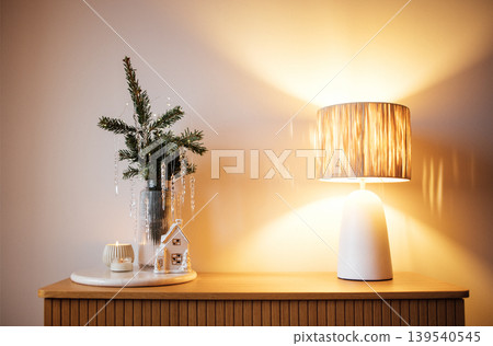 Cozy interior scene featuring a decorative lamp, small evergreen plant, and candle on a wooden table, creating a warm and inviting atmosphere for home decor inspiration Cozy interior scene featuring a decorative lamp, small evergreen plant, and candle on a wooden table, creating a warm and inviting atmosphere for home decor inspiration 139540545