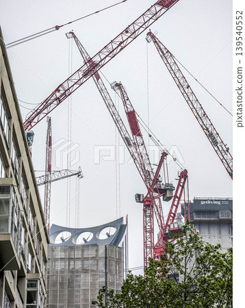 Multiple Tower Cranes Surrounding High Rise Construction Project in Dense Urban Environment Under Overcast Sky Multiple Tower Cranes Surrounding High Rise Construction Project in Dense Urban Environment Under Overcast Sky 139540552
