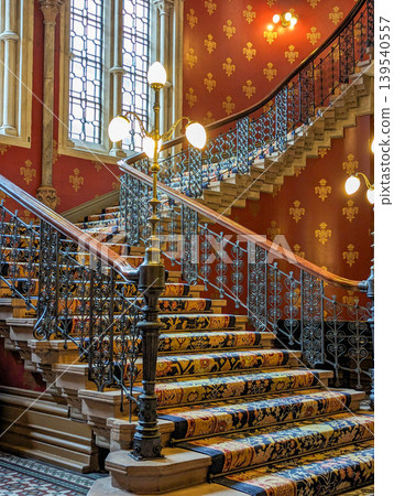 Ornate Historic Staircase Interior with Decorative Iron Railings Patterned Carpet  139540557