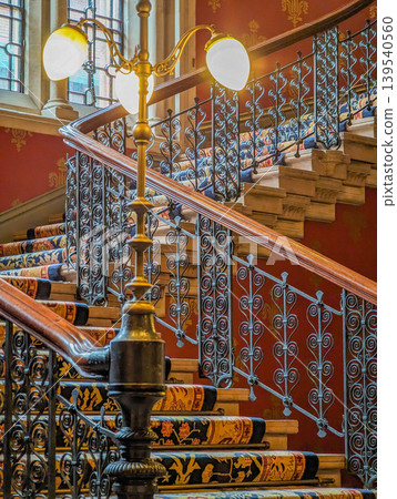 Ornate Historic Staircase Interior with Decorative Iron Railings Patterned Carpet Ornate Historic Staircase Interior with Decorative Iron Railings Patterned Carpet 139540560