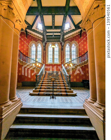 Ornate Historic Staircase Interior with Decorative Iron Railings Patterned Carpet Ornate Historic Staircase Interior with Decorative Iron Railings Patterned Carpet 139540561