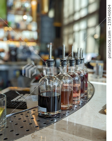 Glass Bottles with Pour Spouts on Bar Counter in Restaurant Setting with Blurred Background Glass Bottles with Pour Spouts on Bar Counter in Restaurant Setting with Blurred Background 139540604