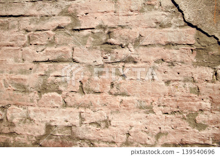 Old pink textured crumbling wall made of bricks plastered with brown clay Old pink textured crumbling wall made of bricks plastered with brown clay 139540696