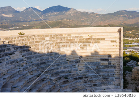 Ancient stone amphitheater ruins at sunset with a mountain landscape Ancient stone amphitheater ruins at sunset with a mountain landscape 139540836