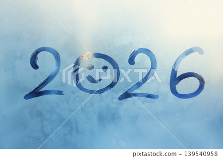 Handwritten blue arabic numerals 2026 is twenty twenty-six with doodle smiling face on frozen window, copy space Handwritten blue arabic numerals 2026 is twenty twenty-six with doodle smiling face on frozen window, copy space 139540958